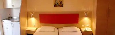 a bedroom with two beds and a red wall at Philoxenia Hotel & Studios in Rhodes Town