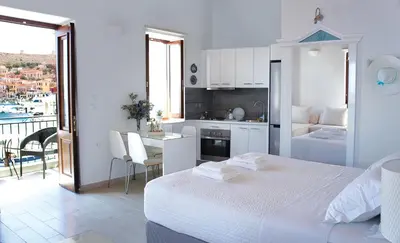 a bedroom with a bed and a kitchen with a balcony at Aegean View Villas in Halki