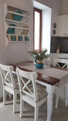 a white kitchen with a wooden table and chairs at Aegean View Villas in Halki