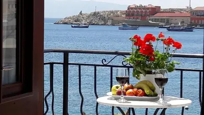 a table with a plate of fruit and flowers on a balcony at Aegean View Villas in Halki