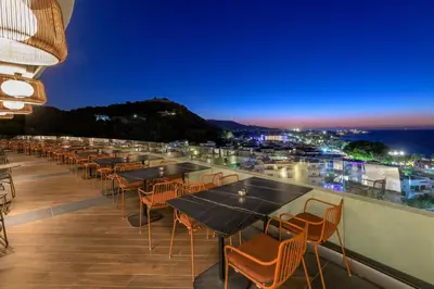 a row of tables and chairs on a roof at night at Olympic Palace Hotel in Ixia