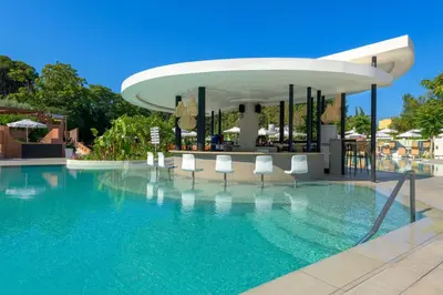 a swimming pool with white chairs and a building at Olympic Palace Hotel in Ixia