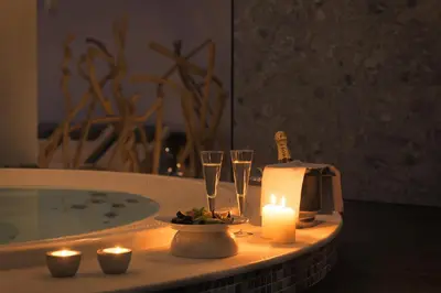 a bath tub with a candle and two glasses of wine at Olympic Palace Hotel in Ixia