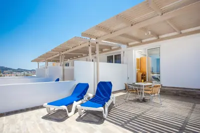a patio with blue chairs and a table on a roof at Mon Repos Hotel in Faliraki