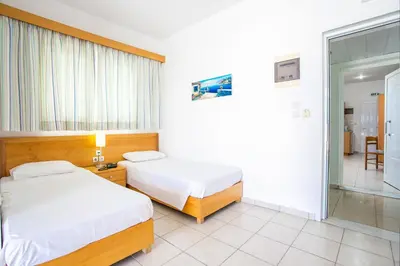 a bedroom with two beds and a sliding glass door at Mon Repos Hotel in Faliraki