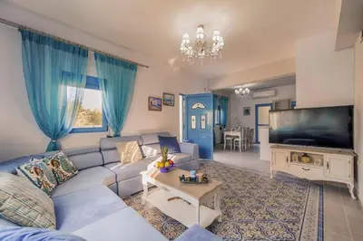 a living room with a couch and a flat screen tv at Lindos Luxury Retro Villas in Líndos