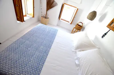 a bedroom with a white bed and a blue rug at Lindos Esel Suites in Líndos