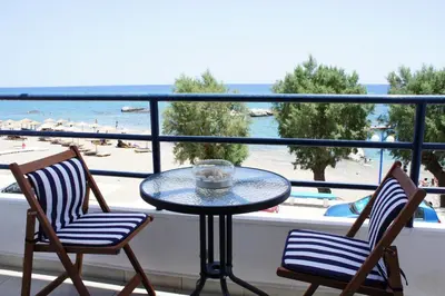 a table on a balcony with a view of a beach at Rodos Beach in Archangelos