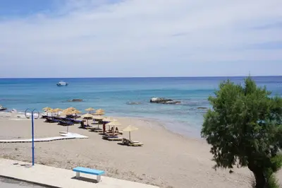 a beach with chairs and umbrellas and the ocean at Rodos Beach in Archangelos
