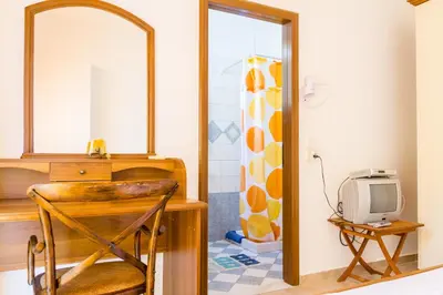 a room with a desk with a mirror and a television at Kaya Sea Studios - Stegna Beach in Archangelos