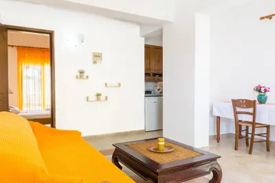 a living room with a yellow couch and a table at Kaya Sea Studios - Stegna Beach in Archangelos