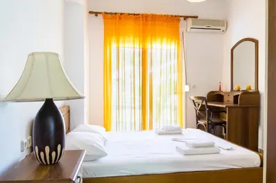 a bedroom with a bed with a lamp and a desk at Kaya Sea Studios - Stegna Beach in Archangelos
