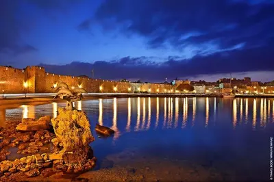 a large body of water at night with a city at The old town Neighbourhood in Rhodes Town