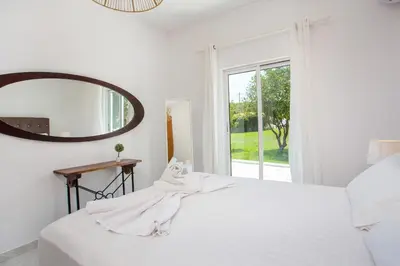 a white bedroom with a large white bed and a mirror at Mythos Luxury Villa in Faliraki