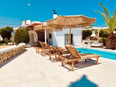 a row of chairs and umbrellas next to a swimming pool at Mythos Luxury Villa in Faliraki