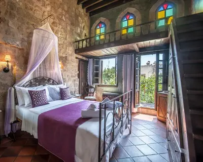 a bedroom with a bed in a room with stained glass windows at S.Nikolis' Historic Boutique Hotel in Rhodes Town