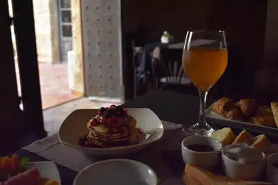 a table with a plate of pancakes and a glass of orange juice at S.Nikolis' Historic Boutique Hotel in Rhodes Town