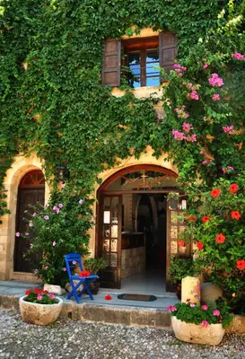 a house with flowers and a blue chair in front of it at S.Nikolis' Historic Boutique Hotel in Rhodes Town