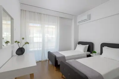 a white room with two beds and a window at Harmony Elegant Central Apartment in Rhodes Town