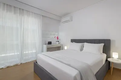 a white bedroom with a large bed with white pillows at Harmony Elegant Central Apartment in Rhodes Town