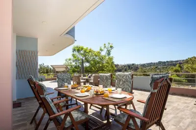 a wooden table and chairs on a deck with a view at Athina's Villa with heated pool in Koskinou