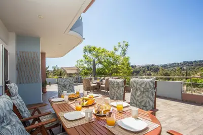a dining table and chairs on a deck with a view at Athina's Villa with heated pool in Koskinou