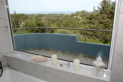a bathroom with a large window and a bath tub at Athina's Villa with heated pool in Koskinou