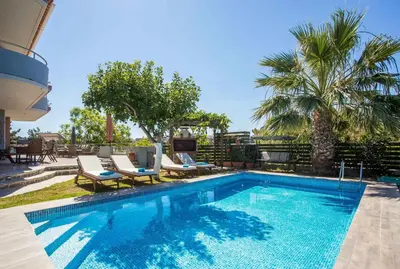 a swimming pool with lounge chairs and a palm tree at Athina's Villa with heated pool in Koskinou