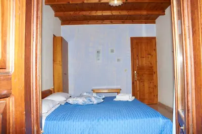 a bedroom with a blue bed and a wooden door at Kamares Studios in Symi