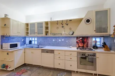 a kitchen with white cabinets and blue tiles at Villa Sole Mare in Pefki Rhodes