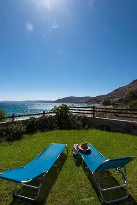two blue beach chairs sitting on the grass near the ocean at Villa Sole Mare in Pefki Rhodes