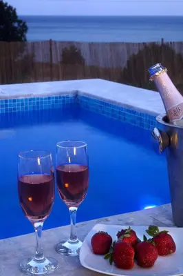 two glasses of wine and strawberries next to a swimming pool at Blue Dream Exclusive villas privees in Pefki Rhodes
