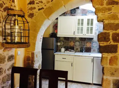 a kitchen with white cabinets and a stone wall at George & Alexandra's Apartments in Rhodes Town