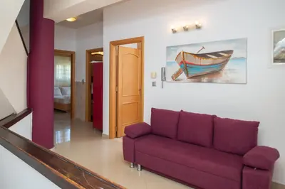 a living room with a purple couch and a painting of a boat at Villa Elia in Kolimbia