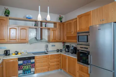 a kitchen with wooden cabinets and a stainless steel refrigerator at Villa Elia in Kolimbia
