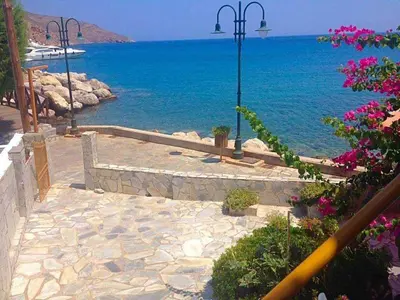 a stone walkway next to the water with flowers at Spiros Apartments in Livadia