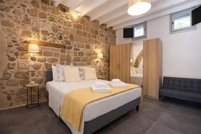 a bedroom with a bed and a stone wall at The Old Town House in Rhodes Town