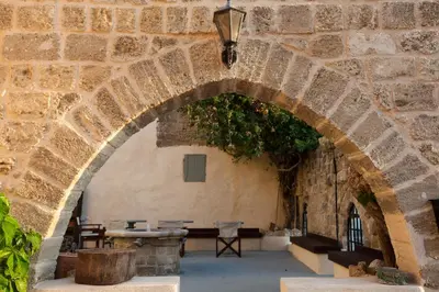 an archway in a stone building with a table and benches at The Old Town House in Rhodes Town