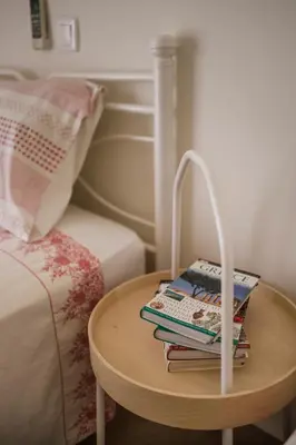 a table with books on it next to a bed at The Corner House at Gennadi Court in Gennadi