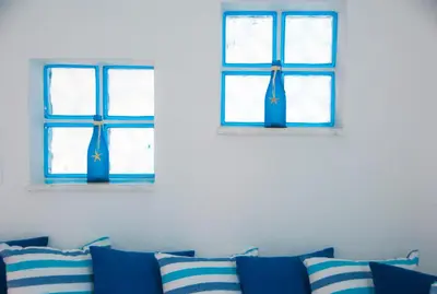 two windows in a white room with blue pillows at Carpe Diem Studios in Ialyssos