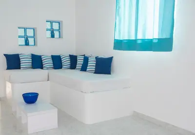 a white couch with blue pillows on a white wall at Carpe Diem Studios in Ialyssos
