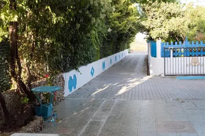 a sidewalk with a blue fence and a tree at Carpe Diem Studios in Ialyssos