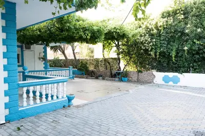 a blue house with a white fence and trees at Carpe Diem Studios in Ialyssos