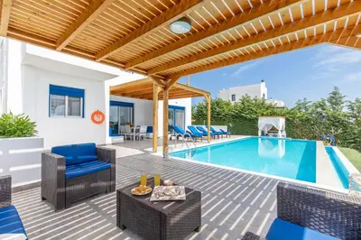 an outdoor patio with a pool and chairs at White Blue Villa in Lachania