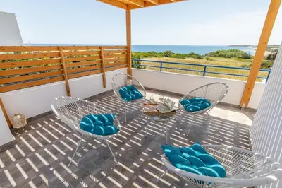 a balcony with chairs and a table and the ocean at White Blue Villa in Lachania