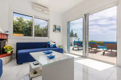 a living room with a blue couch and a view of the ocean at White Blue Villa in Lachania