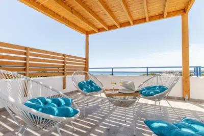 a patio with chairs and a table with a view of the ocean at White Blue Villa in Lachania
