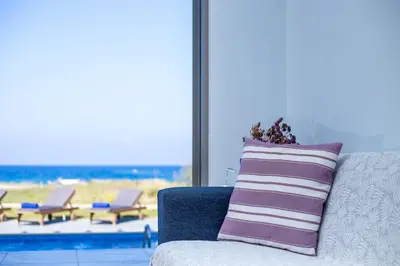 a couch with a pillow and a view of the beach at Rhodes Sea Villas in Ixia