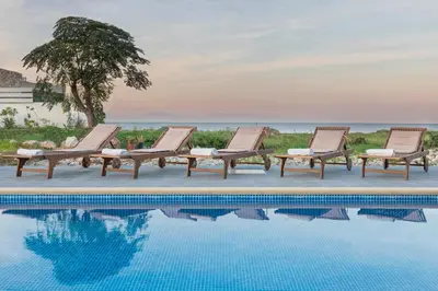 a row of lounge chairs next to a swimming pool at Rhodes Sea Villas in Ixia