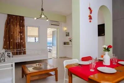 a kitchen and living room with a red table and chairs at St Peter & Paul at haraki in Haraki